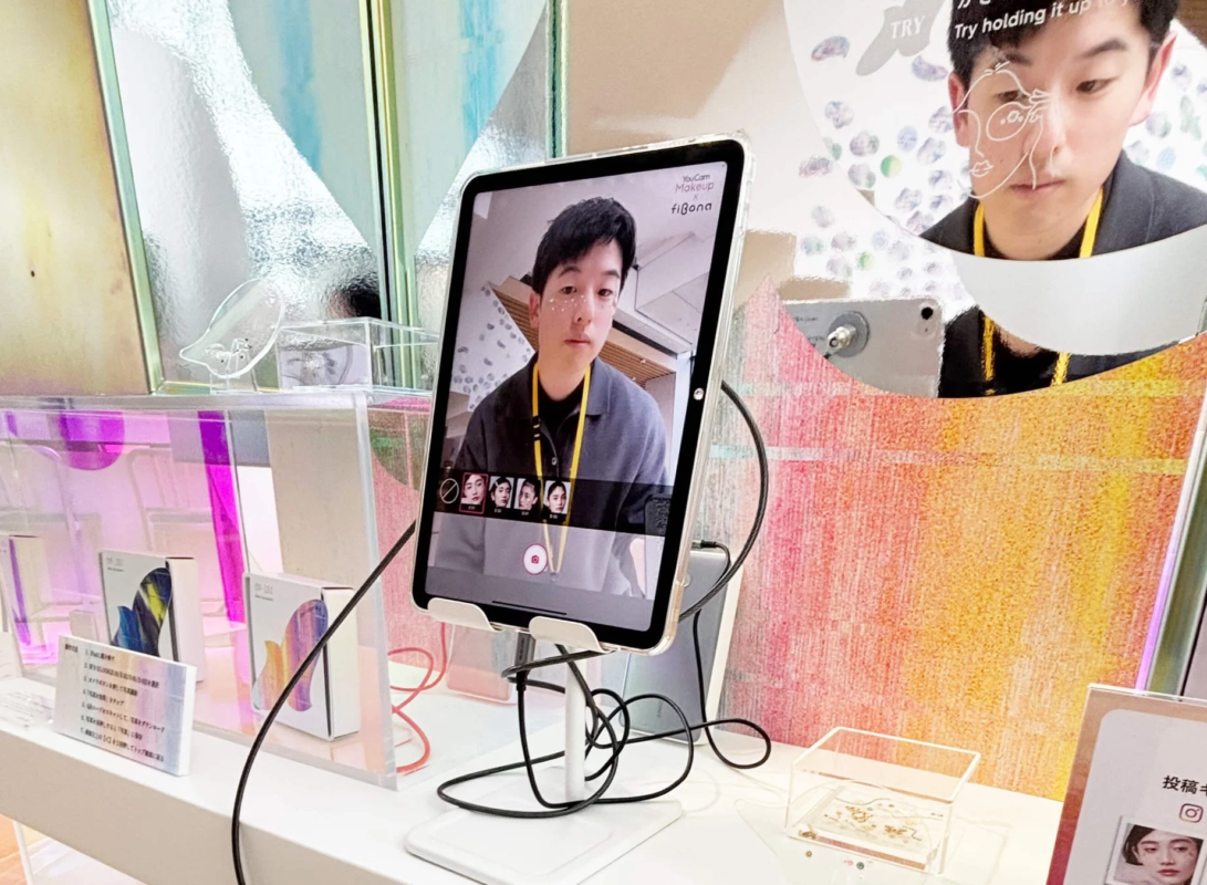 Hombre prob&aacute;ndose maquillaje virtual AR en una tablet en un stand de experiencia