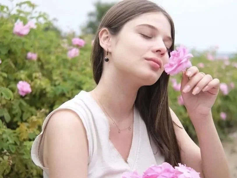 Mujer oliendo una rosa en un jard&iacute;n