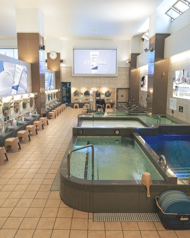 Interior del baño público con publicidad de AESTURA