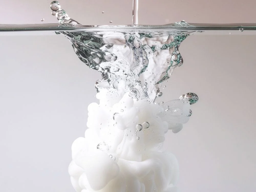 Líquido blanco difundiéndose en agua
