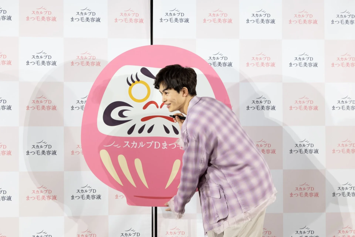 Takuya Kusakawa dibujando las pesta&ntilde;as del daruma