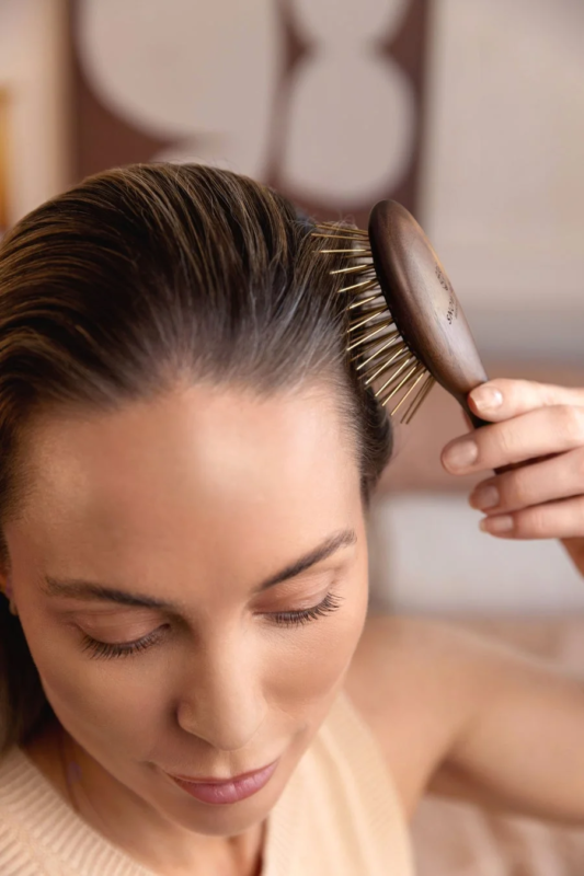 Mujer cepillándose el cabello con un cepillo de madera