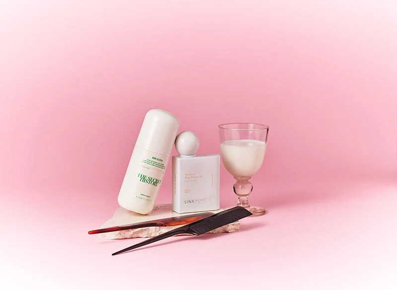 Productos de belleza y peine en un fondo rosa