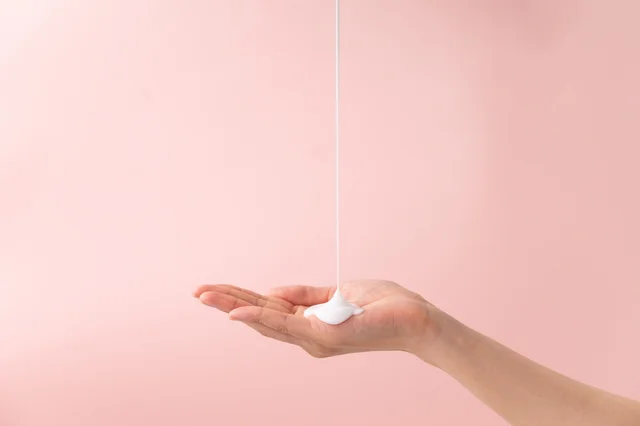 Crema o loción blanca vertiéndose en la palma de la mano
