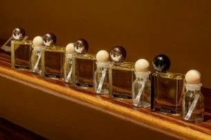 Colecci&oacute;n de frascos de perfume alineados en una superficie de madera