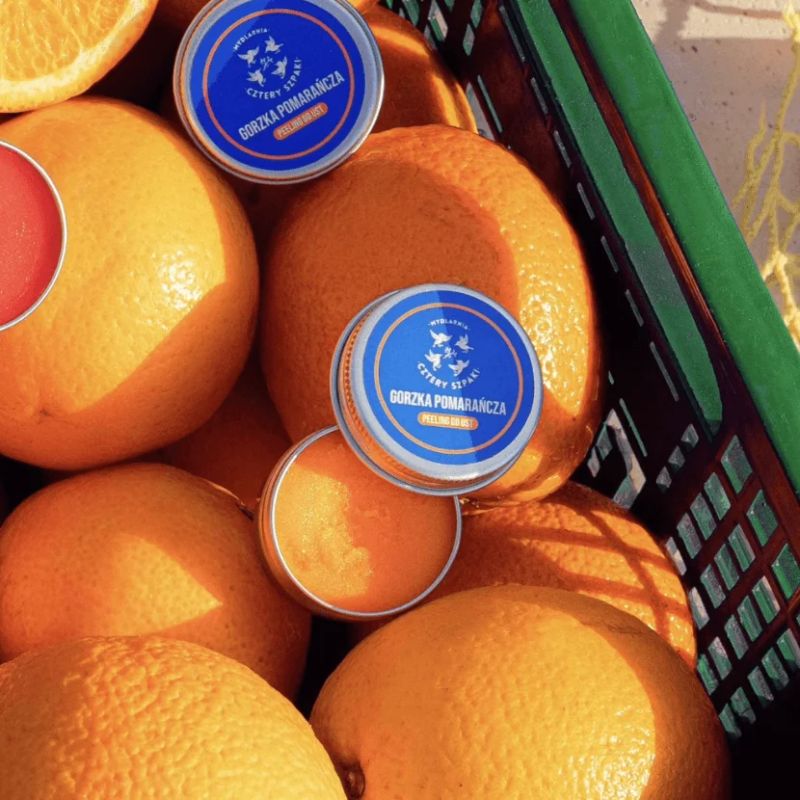 Exfoliante labial de naranja amarga de 4Starlings en una caja llena de naranjas