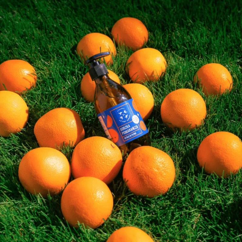 Botella de jab&oacute;n l&iacute;quido de naranja amarga de 4Starlings sobre c&eacute;sped con naranjas