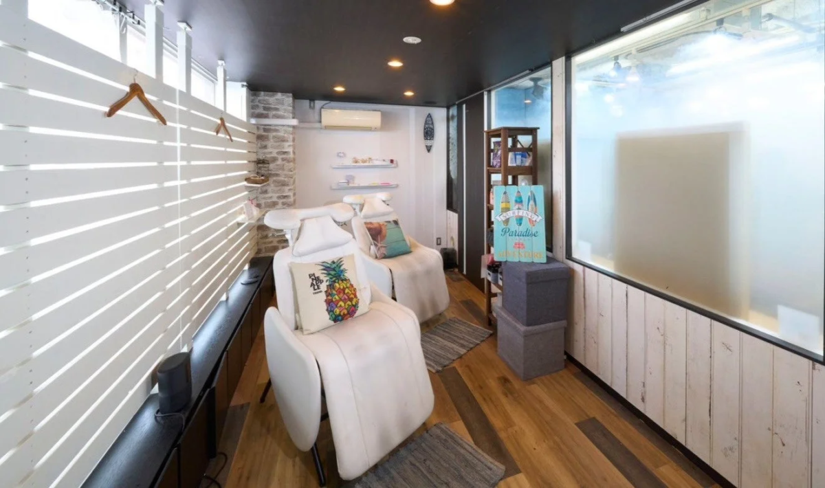 Interior de un sal&oacute;n con sillas reclinables y decoraci&oacute;n tropical