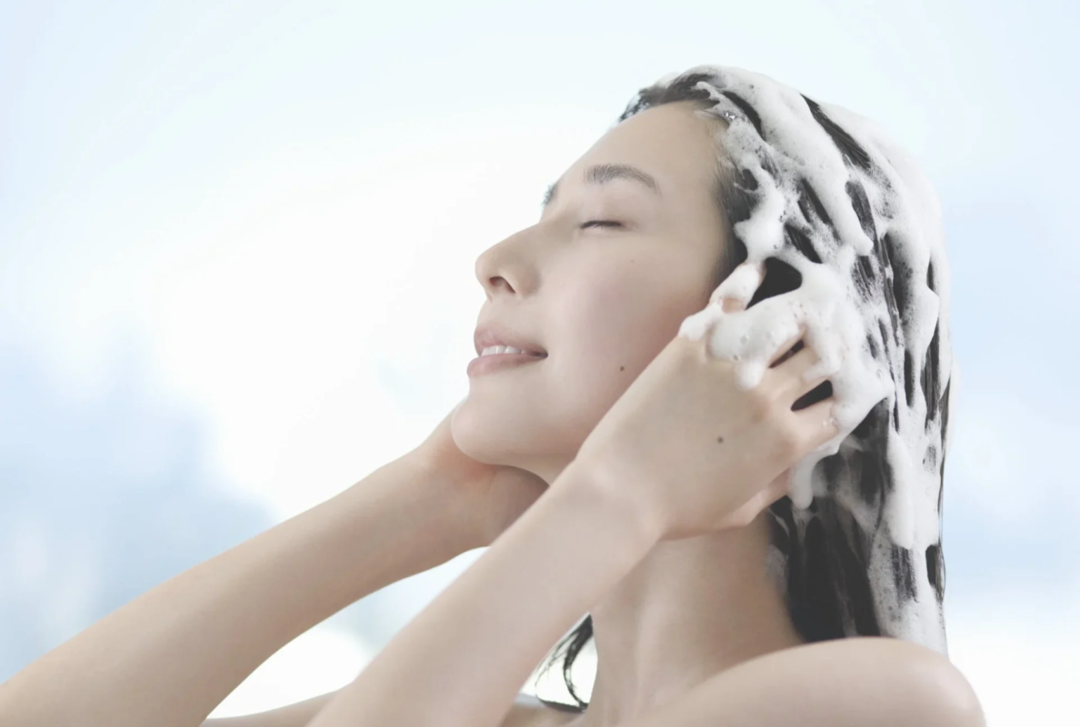 Mujer lav&aacute;ndose el cabello con abundante espuma