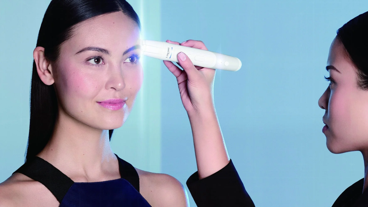 mujer utilizando un dispositivo de belleza en su frente