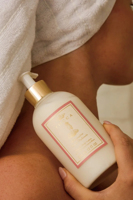 Mujer con toalla sosteniendo TOCCA Cleopatra Hand & Body Lotion