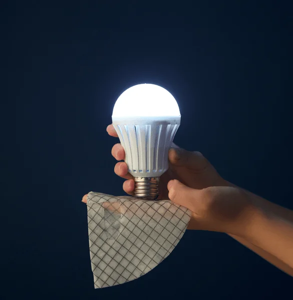 Manos sosteniendo una bombilla LED, imagen que sugiere tecnolog&iacute;a
