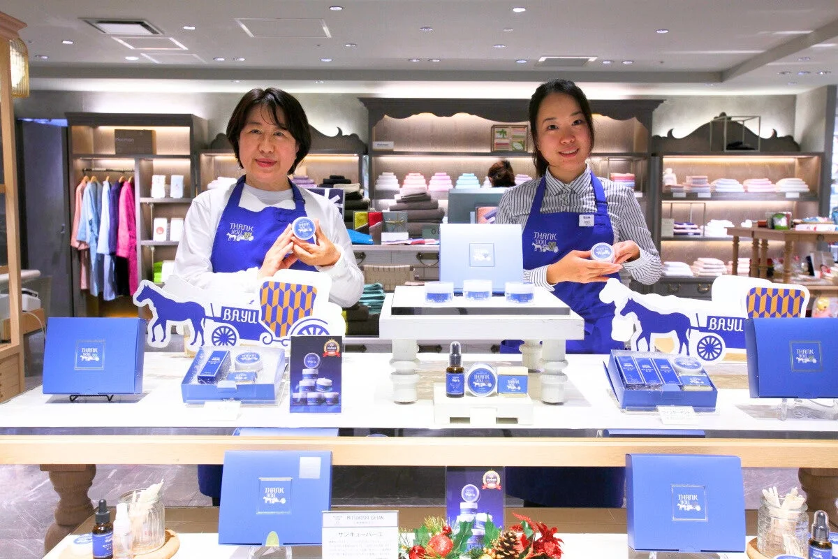 Dos mujeres sonriendo con productos THANK YOU BAYU en la tienda