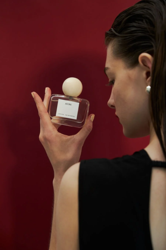 Mujer sosteniendo una botella de perfume