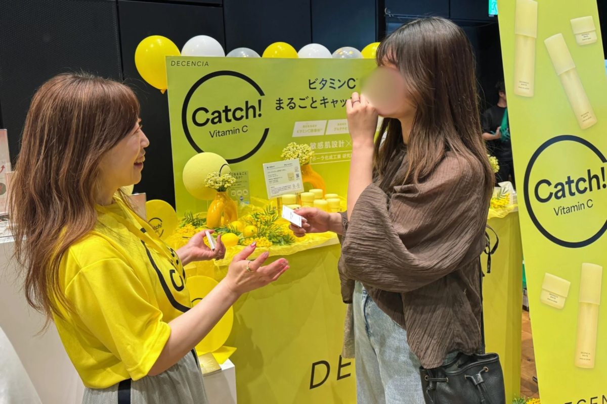 Presidenta de DECENCIA, Emi Nishino, interactuando con asistentes en el stand