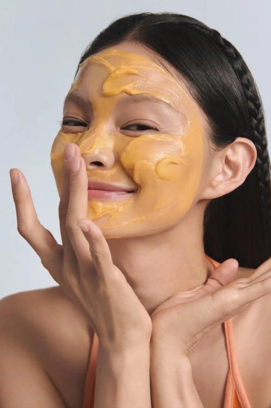 Mujer sonriendo con mascarilla facial