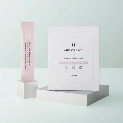 Caja y un sobre individual del suplemento And Creage Soy Bloom Stick Powder, con información de ingredientes.