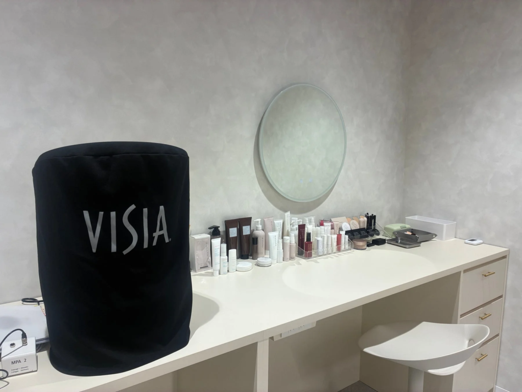 Espacio de belleza con espejo redondo y productos de skincare, incluyendo un dispositivo VISIA