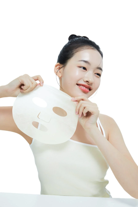 mujer sonriendo con mascarilla en la mano