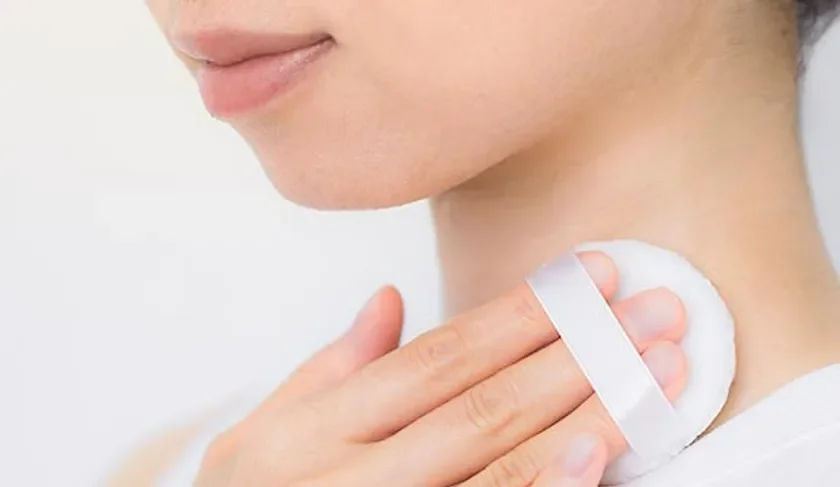 Mujer aplicando polvo en el cuello